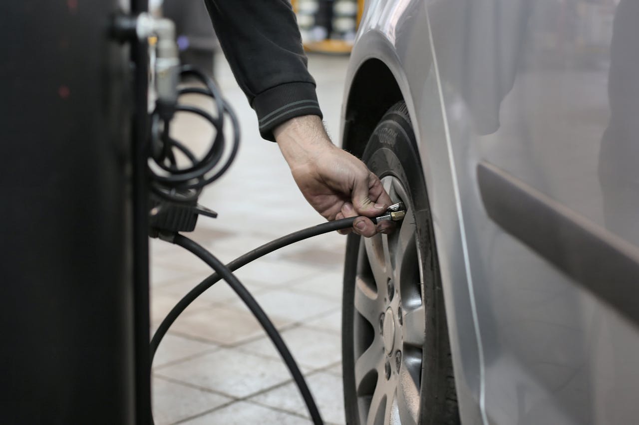 Mechanic inflating a car tire inside an auto repair shop, ensuring optimal tire pressure.